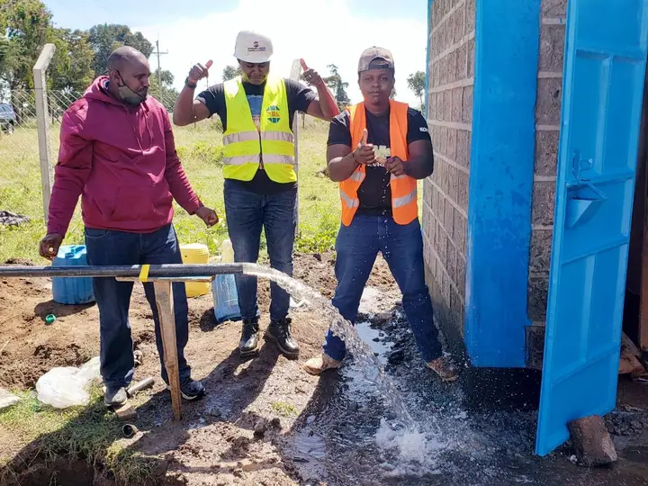 People beside flowing water at the Isiolo WASH site.